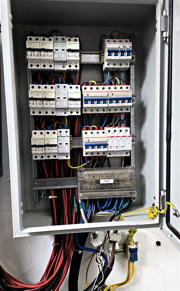 Coffret électrique ouvert avec disjoncteurs multiples et câbles colorés