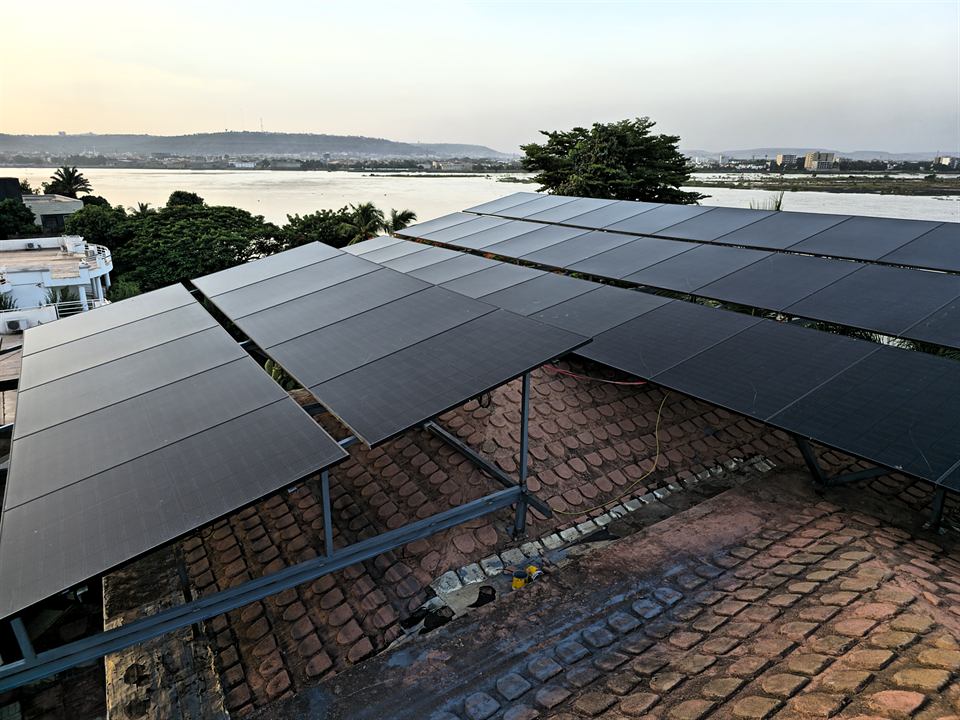 Deux rangées de modules solaires sur charpente métallique, toiture en tuiles en dessous