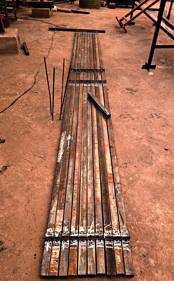 Tubes d'acier alignés sur le sol, à côté de structures en cours de fabrication