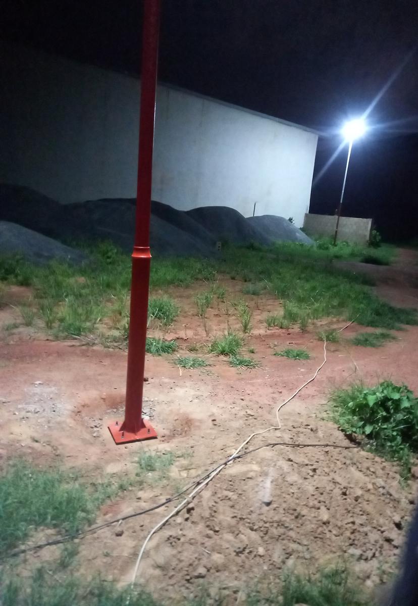 Pied de mât rouge et projecteur allumé, de nuit