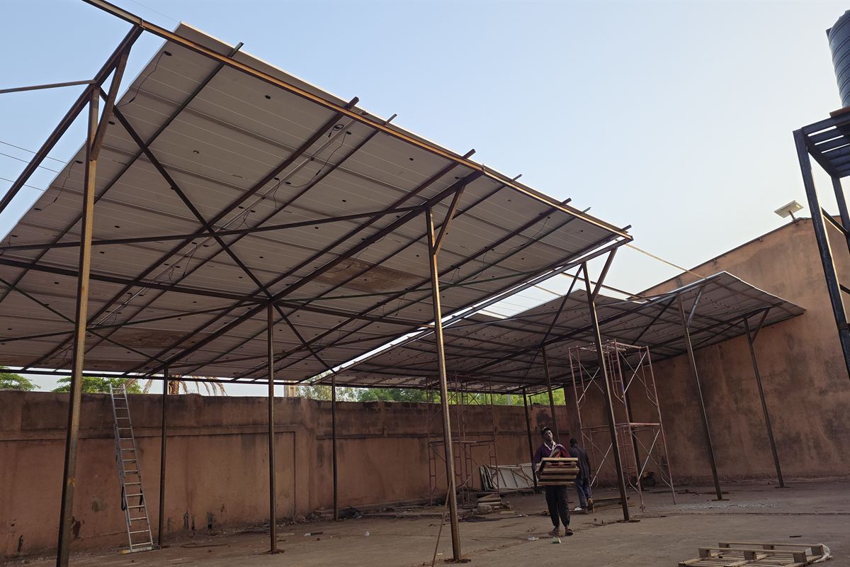 Charpente métallique portant des modules photovoltaïques, montée dans une cour